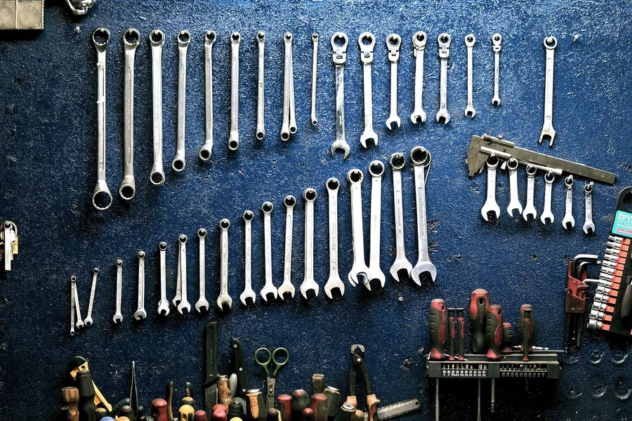 Wall of wrenches hanging on a blue pegboard