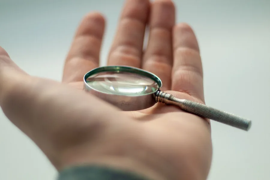 Hand-held magnifying glass resting on a workbench